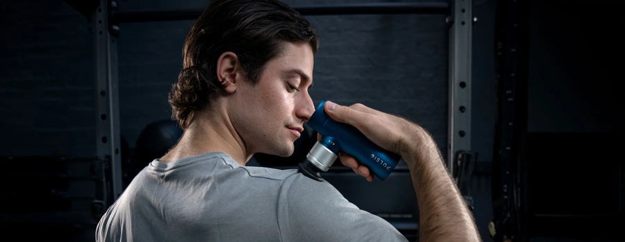 Person using a blue massage gun on their shoulder.